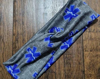 May include: Gray headband with a blue and white star of life pattern. The headband is made of a soft, stretchy fabric and is perfect for keeping your hair out of your face.