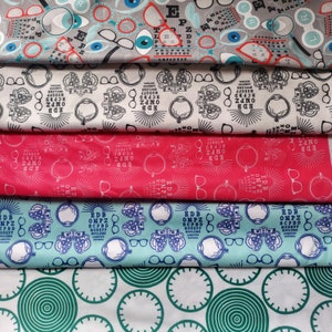 May include: A collection of fabric swatches with eye-themed patterns. Designs include eyeglasses, eye charts, and stylized eye illustrations in various colors like gray, red, and blue. The fabric is suitable for crafting or sewing projects.