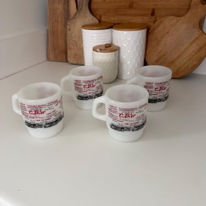 May include: Four white milk glass mugs featuring black and red text and graphics related to CB radio terminology. Each mug displays the text C.B.'er along with various phrases like 10-4, Smokey Bear, and Drop the Hammer, arranged in a circular pattern.