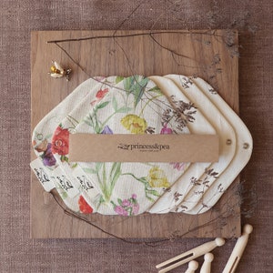 May include: Set of four organic cloth pads with a floral print featuring yellow, pink, and purple flowers. The pads are packaged with a brown paper label that reads "princess&pea organic cloth pads".