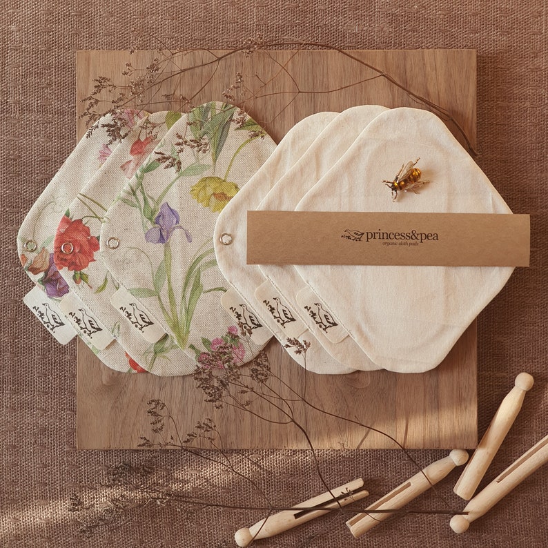 May include: Set of five reusable cloth pads with floral print and a brown paper tag with the text "princess&pea organic cloth pads".