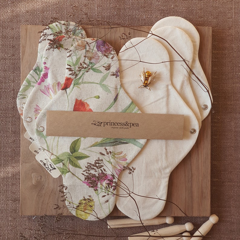 May include: A set of reusable cloth pads with a floral print and a brown label that reads "princess&pea organic cloth pads".