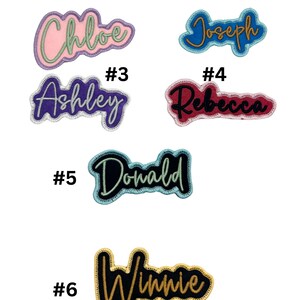 May include: Six embroidered iron-on patches with different names, including Chloe, Joseph, Ashley, Rebecca, Donald, and Winnie. The patches are in various colours, including pink, blue, purple, red, black, and gold.