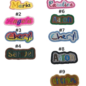 May include: Nine embroidered iron-on patches with different names, including Maria, Caroline, Angela, Aaron, Cheryl, Samuel, and Charles. The patches are in various colours and styles.