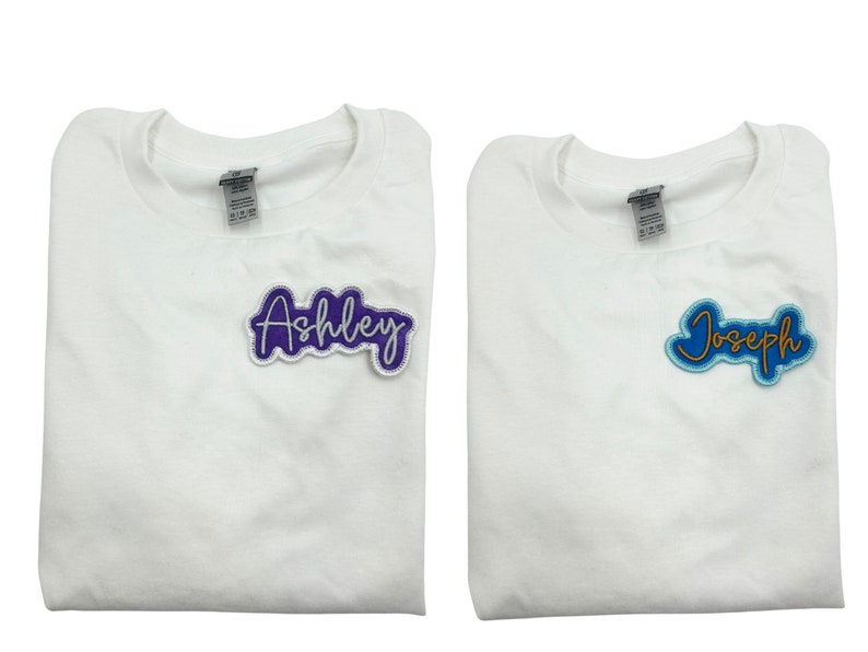 May include: Two white t-shirts with personalized names. The left shirt has a purple "Ashley" patch. The right shirt has a blue "Joseph" patch.