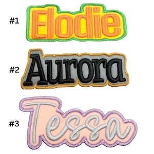 Peut inclure: Trois patchs brodés thermocollants avec les noms : Elodie en jaune et vert, Aurore en gris et noir, et Tessa en rose et violet.