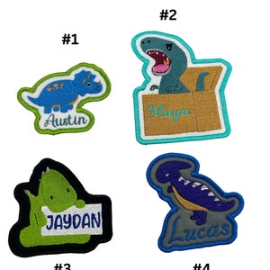 May include: Four embroidered iron-on patches featuring dinosaurs with names. The first patch is blue and green with the name "Austin". The second patch is blue, green, and brown with the name "Maya". The third patch is green and black with the name "Jaydan". The fourth patch is purple, grey, and blue with the name "Lucas".