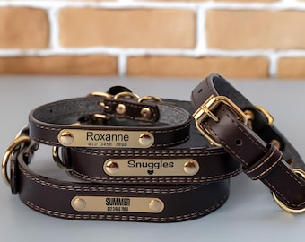 May include: Three brown leather dog collars with gold metal buckles and engraved name tags. The name tags read "Roxanne 012 3456 7890", "Snuggles" and "Summer 012 3456 7890".