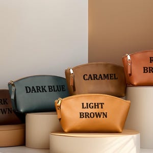 K&ouml;nnte beinhalten: Eine wei&szlig;e Keramik-Tasse mit schwarzem Henkel und dem Text "But First, Coffee" in fetter, schwarzer Schrift. Die Tasse steht vor einem verschwommenen Hintergrund, der ihr klares Design hervorhebt.