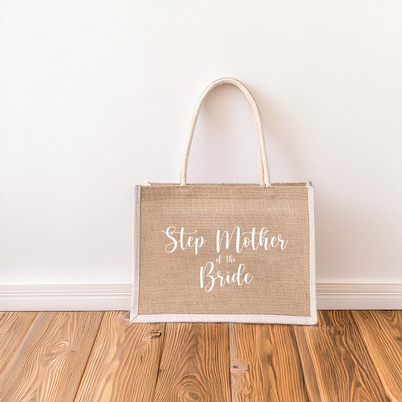 Pode incluir: Uma bolsa de compras de juta bege com al&ccedil;as brancas e o texto "Step Mother of the Bride" impresso na frente.