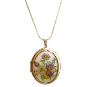 May include: Gold-toned necklace with an oval pendant. The pendant features a floral design in shades of pink, purple, yellow, and orange on a white background. The necklace has a delicate chain.