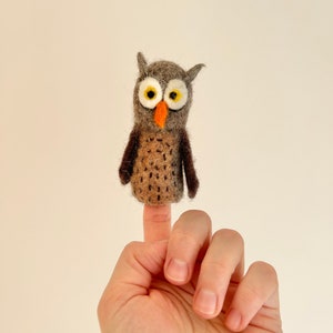 Puede incluir: Un títere de dedo de fieltro marrón y gris con pico naranja y ojos amarillos.