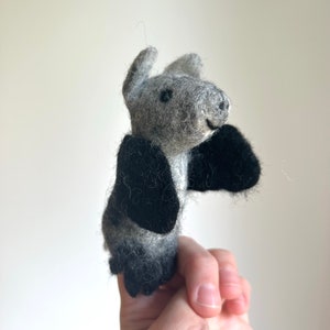 Può includere: Un burattino per dita in feltro grigio e nero a forma di pipistrello con grandi ali nere.