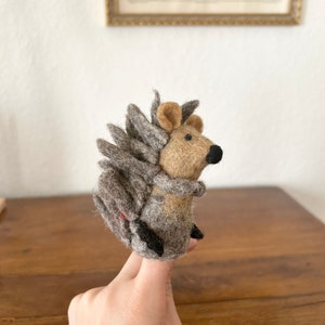 Könnte beinhalten: Eine graue und braune Filz-Fingerpuppe eines Igels mit schwarzen Augen und einer braunen Nase.