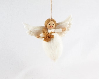 Puede incluir: Un adorno de ángel de fieltro con un vestido blanco y grandes alas blancas. La figura tiene cabello de hilo marrón claro peinado en una trenza, una cara redonda con ojos de puntos negros y una pequeña boca cosida en hilo rojo.