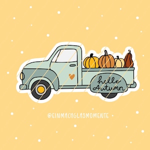 May include: A light blue cartoon truck with pumpkins of different shapes and colours. The truck has a heart detail and the words "hello Autumn" on the side. The background is yellow with white dots.