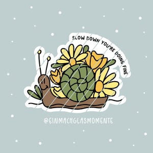 以下が含まれることがあります： 黄色と緑の花束を持った漫画のカタツムリを描いたステッカー。カタツムリの周りに「Slow down you're doing fine」という文字が書かれています。