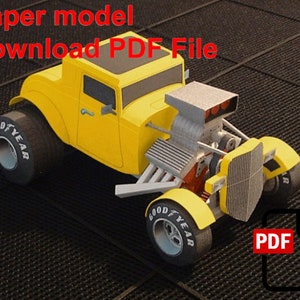 May include: A yellow paper model of a hot rod car with a large engine and "GOOD YEAR" tires. The model is on a black and white checkered background. The text "Paper model Download PDF File" is at the top of the image. A red PDF icon with a download arrow is in the lower right corner.
