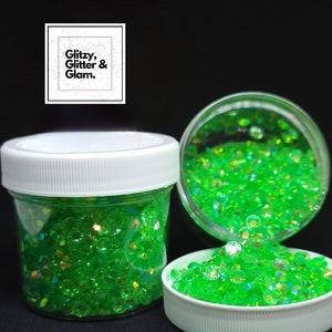 May include: Three jars filled with green iridescent glitter. The jars have white lids. The text "Glitzy, Glitter & Glam." is on a black square.
