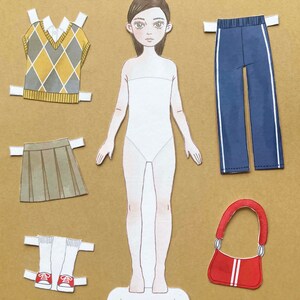 Puede incluir: Mu&ntilde;eca de papel con una variedad de opciones de ropa, incluyendo un chaleco de punto de color amarillo y marr&oacute;n, una falda plisada marr&oacute;n, un pantal&oacute;n azul con rayas blancas, un par de calcetines blancos con zapatillas rojas y un bolso de mano rojo con rayas blancas.