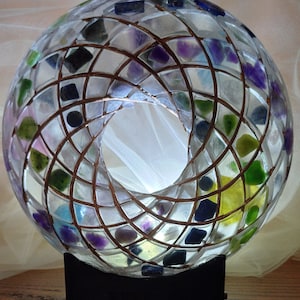 May include: A clear glass sphere nightlight with a copper wire frame and embedded colourful gemstones. The sphere sits on a black base.