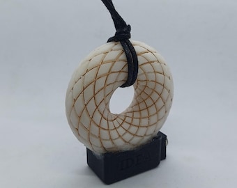 May include: A white pendant necklace with a geometric design, featuring a black cord and a black base with the word "IDEA" inscribed on it.