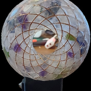 May include: A clear glass sphere with a copper wire design and colorful accents. The sphere is mounted on a black base with a plug.