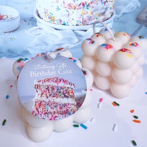 May include: White bubble candle with sprinkles on top. The candle is shaped like a cake and has a tag that says "Buttercup Gifts Birthday Cake Bubble Candle".