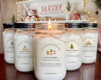 May include: Six glass jar candles with black lids and twine bows. The labels read "Buttercup Gifts Candle Shop" and feature holiday-themed scents like "Santa's Cookies" and "Christmas Morning." Each candle is 16 oz.
