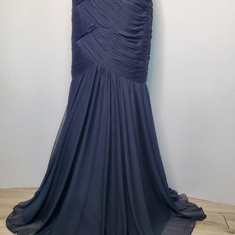May include: A navy blue floor-length gown with a pleated bodice and a flowing skirt.