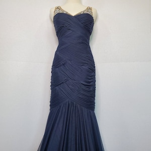 May include: A navy blue, floor-length, sleeveless gown with a sweetheart neckline and a beaded bodice.