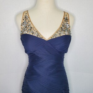 May include: A navy blue sleeveless dress with a beaded neckline. The dress has a fitted bodice and a flowing skirt.