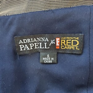 May include: A black dress tag with white text that reads "Adrianna Papell for E! Red Carpet". The tag also has a smaller white tag with black text that reads "6 Made in China".