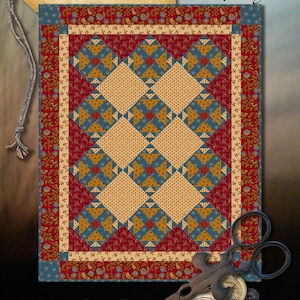 Pode incluir: Um padrão de colcha chamado "Fox and Geese" de Wagon West Designs. O padrão apresenta um design geométrico vermelho, azul e amarelo sobre um fundo branco. A colcha mede 91 cm por 113 cm.