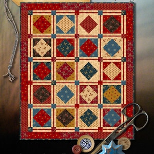 Pode incluir: Um padrão de colcha chamado "Prairie Pop Art" da Wagons West Designs. A colcha é feita de quadrados vermelhos, azuis, amarelos e marrons com um fundo branco. A colcha mede 24 polegadas por 29 polegadas e faz parte da coleção Wagons West Designs.