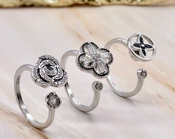 May include: Three silver rings with different designs. The first ring features a flower with clear stones, the second ring has a flower with clear stones, and the third ring has a star design.