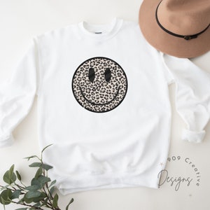 Peut inclure: Sweat-shirt blanc avec un motif de smiley en imprim&eacute; l&eacute;opard noir et marron.