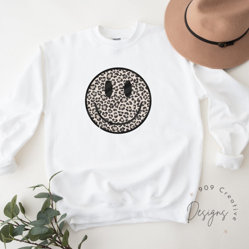 Peut inclure: Sweat-shirt blanc avec un motif de smiley en imprim&eacute; l&eacute;opard noir et marron.