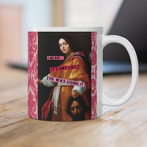 May include: White ceramic mug featuring a classical painting with the text "I mean... It's not like he was using it." The mug has a pink floral pattern on the side.