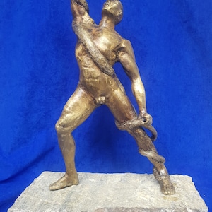 Könnte beinhalten: Eine Bronzeskulptur eines Mannes, der mit einer Schlange ringt. Der Mann ist in einer dynamischen Pose dargestellt, mit erhobenen Armen über seinem Kopf, während er versucht, die Schlange zu bezwingen. Die Skulptur ist auf einem grob behauenen Steinsockel montiert.