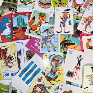 May include: A collection of vintage playing cards with various illustrations. The cards feature images of animals, people, and objects, including a kangaroo, fox, lamb, clown, and mouse. Some cards have text, such as "Wooly Lamb" and "Brown Mouse."