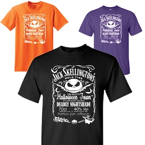 May include: Three t-shirts with a white graphic print of Jack Skellington from the movie The Nightmare Before Christmas. The graphic is a parody of a liquor bottle label. The text on the label reads "Jack Skellington's Mold Time Halloween Town Pumpkin Mash Deadly Nightshade 70cl 40% Vol. Distilled & Bottled by Pumpkin King Distillery". The t-shirts are black, orange, and purple.
