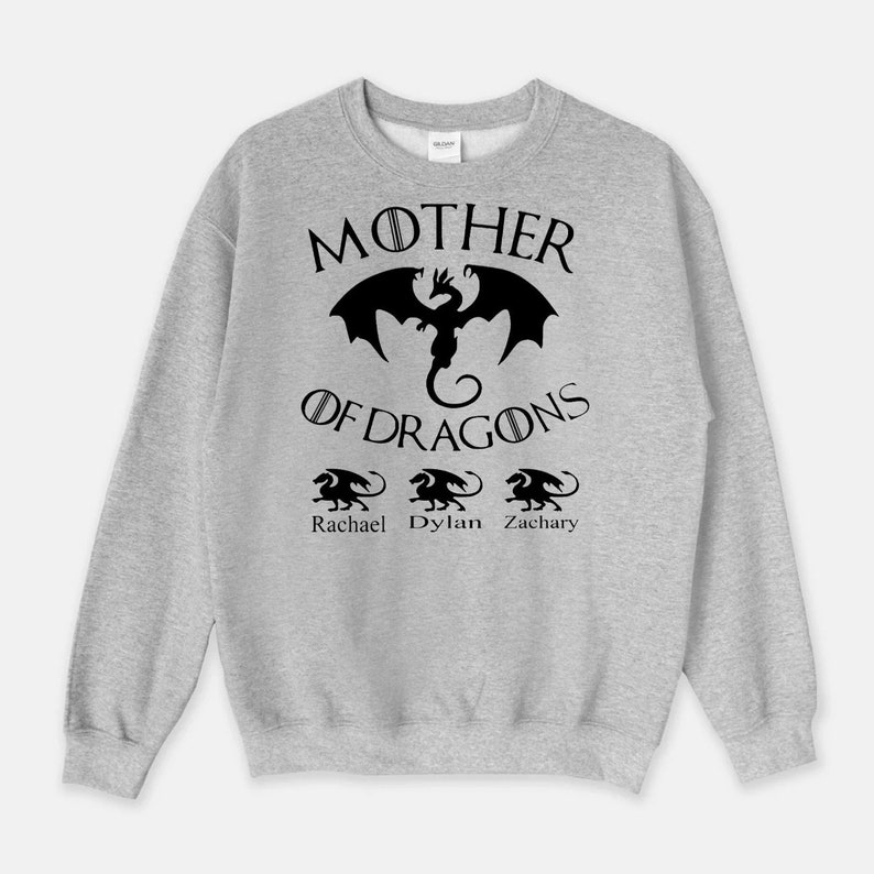 Pu&ograve; includere: Felpa grigia con il testo "Mother of Dragons" e una grafica di drago nero. Sotto il testo ci sono tre grafiche di draghi pi&ugrave; piccole con i nomi "Rachael", "Dylan" e "Zachary" sotto.