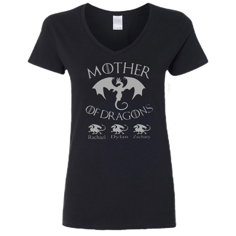 Pu&ograve; includere: Maglietta nera a collo a V con una grafica argentata di un drago e il testo "Mother of Dragons". Sotto il drago ci sono tre draghi pi&ugrave; piccoli con i nomi "Rachael", "Dylan" e "Zachary" sotto.