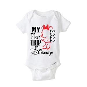 May include: White baby onesie with the text "MY FIRST TRIP to Disney 2022" in black and red. A Minnie Mouse graphic is on the right side. The onesie has short sleeves and a snap closure.