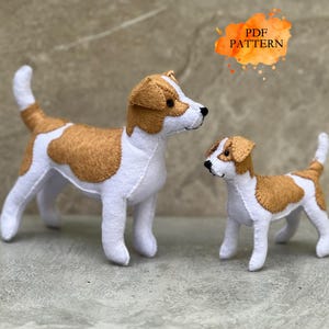 Könnte beinhalten: Zwei handgefertigte Filzhunde-Figuren in Weiß und Hellbraun, bestehend aus einem größeren und einem kleineren Hund, die nebeneinander stehen. Der Text PDF PATTERN ist oben rechts zu sehen. Beide Hunde haben gestickte Details und braune Ohren.