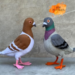May include: Two handcrafted felt pigeon figures. One is brown and white with pink feet, and the other is gray with purple and green neck feathers and orange feet. An orange graphic overlay in the upper right corner displays the text PDF PATTERN.