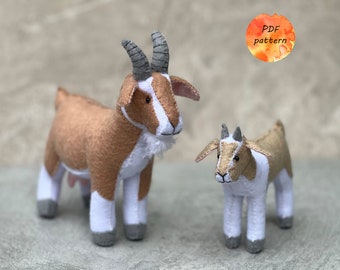 May include: Two felt goat plushies, one larger and one smaller, featuring tan and white bodies with gray horns and hooves. The larger goat has a white beard and visible udder. A circular orange watercolor graphic with the text PDF pattern is visible.