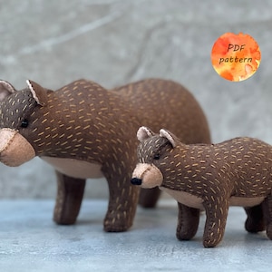 May include: Two brown felt bear figures, a larger adult bear and a smaller cub, stand side-by-side. The bears have tan muzzles, ears, and stitched details. The text "PDF pattern" is in a watercolor circle.