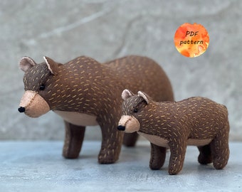 May include: Two brown felt bear figures, an adult and a cub, stand together. The bears have tan muzzles, ears, and stitched details. The text "PDF pattern" is in a watercolour circle.